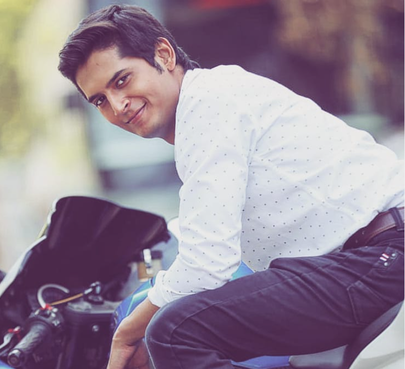 Shalva Kinjawadekar in white shirt sitting on a bike