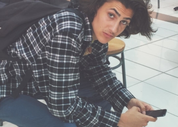 Xander sitting on a chair with his phone