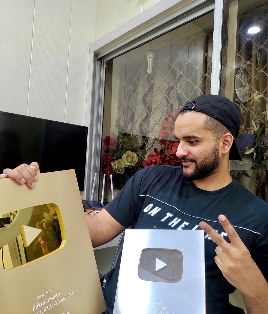 Fukra Insaan with his silver and gold YouTube play buttons. 