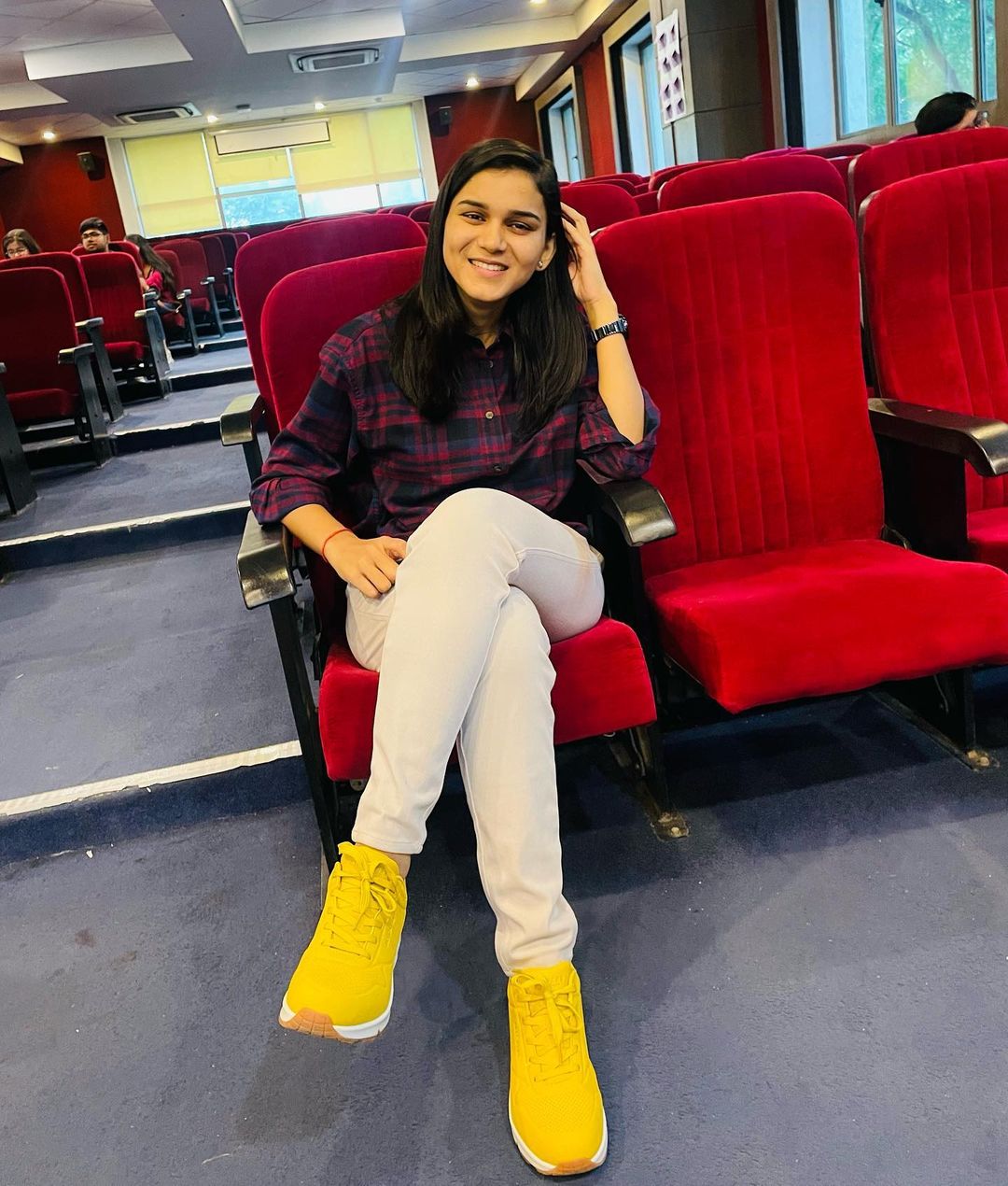 Himanshi sitting on the chair of an auditorium. 