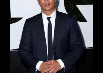 Ismail posing in a black coat and tie.