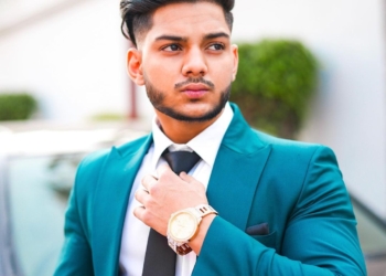 Sehaj Zaildar wearing white shirt, a peacock green color suit and a black tie.
