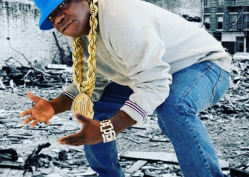 Tracy Morgan wearing a blue hat and jeans and white shirt with gold chain.