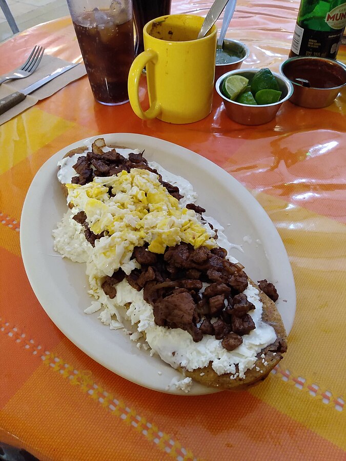 Egg filled Huaraches served on a white colored plate.