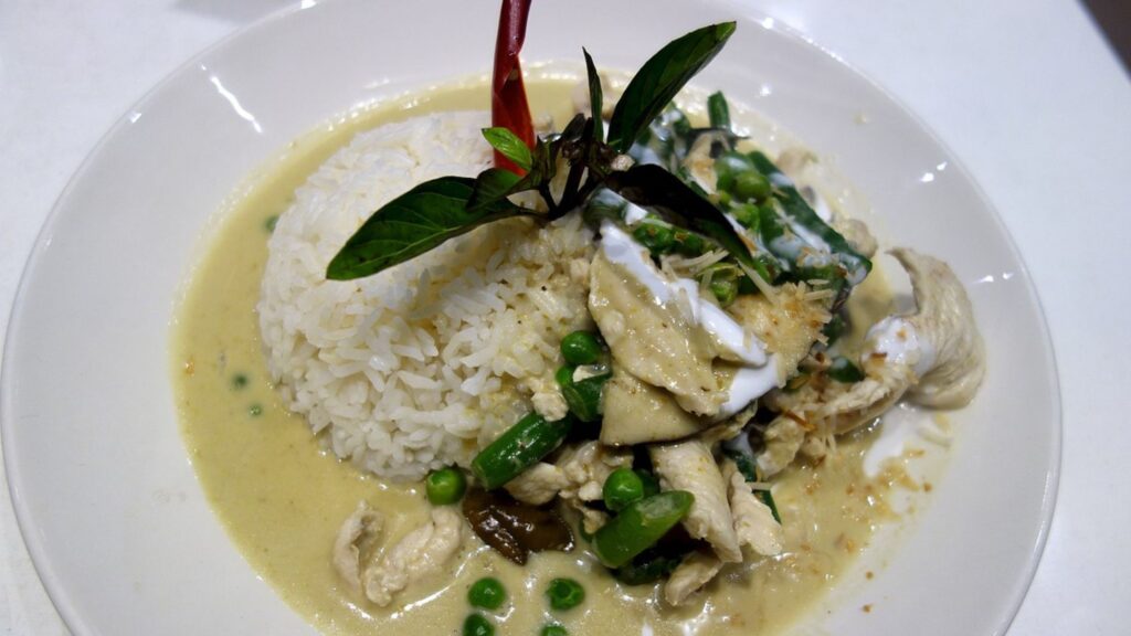 Thai Green Curry served with rice in a white plate.