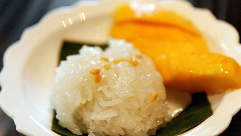Mango sticky rice served on a white plate.