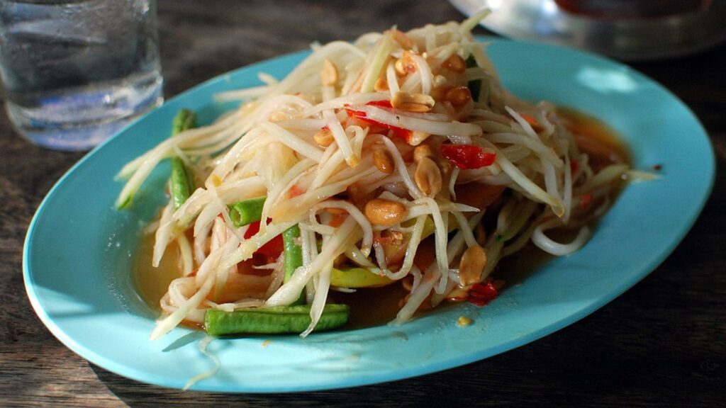 Som Tam salad served on a blue plate.