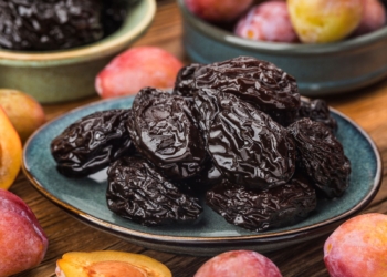 Dry Prunes served on the plate and fresh plum around it.