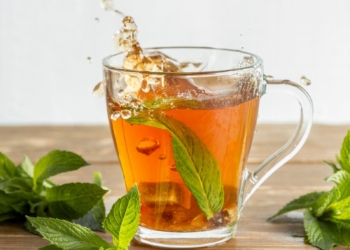 Spearment tea served in a glass cup with a mint leave in it.