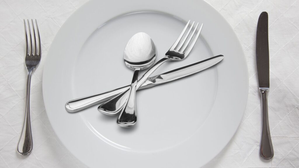 A white plate with fork knife and spoon