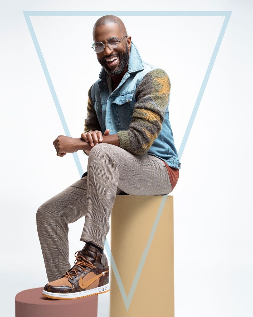 Rickey Smiley wearing blue jacket, printed sweater and light check trouser.