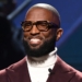 Rickey Smiley wearing white inner and marron colored coat.