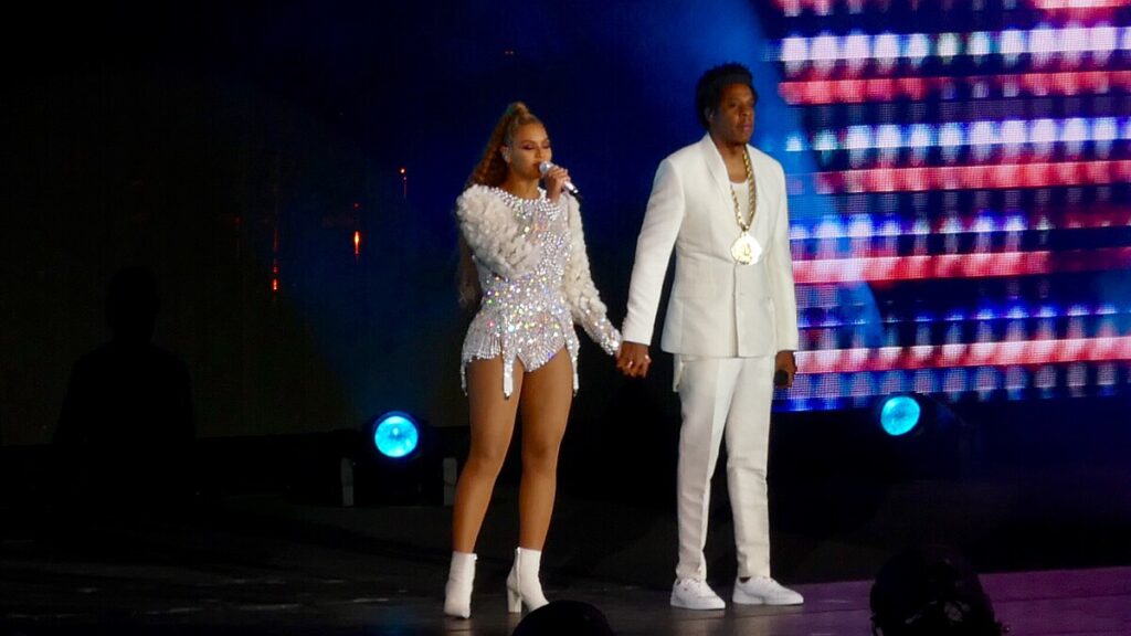 Beyonce and Jay Z together on stage wearing white colored clothes.